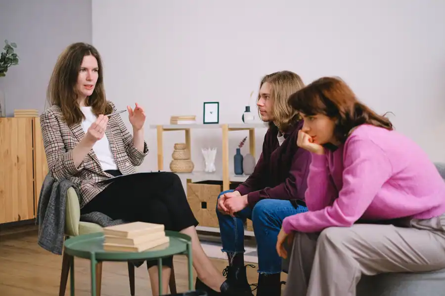 A counselor having a discussion with two students in an inviting, modern interior space.