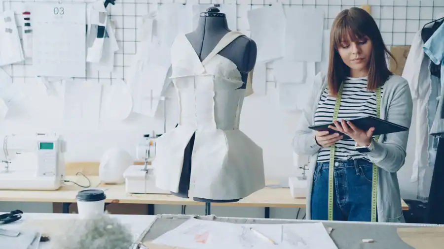 Fashion designer designing dress in stylish studio with sewing tools and mannequin.