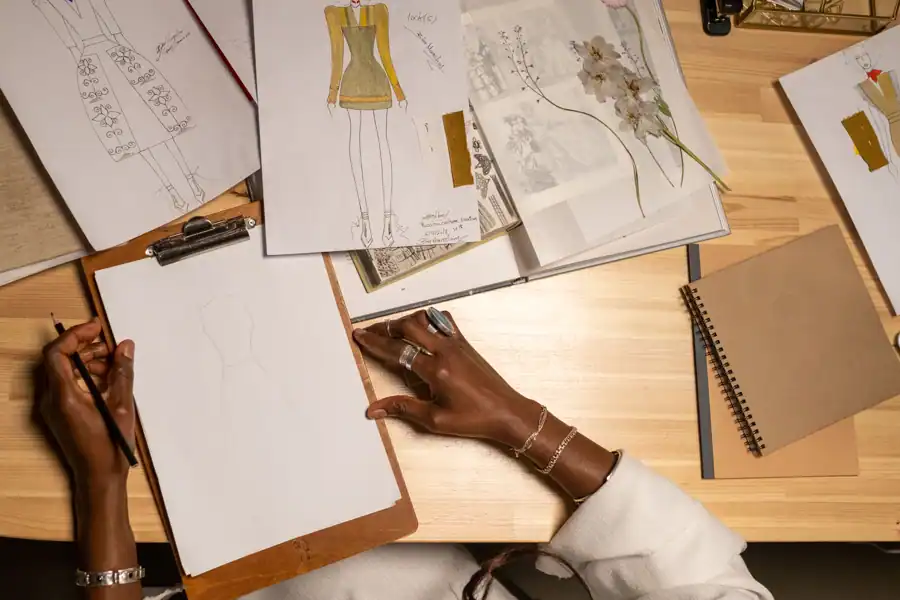 Open fashion design portfolio with sketches and fabric swatches on a studio table
