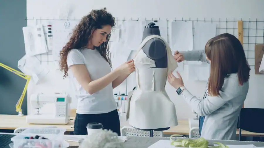 Two women design a dress in a fashion studio, showcasing creativity and teamwork.